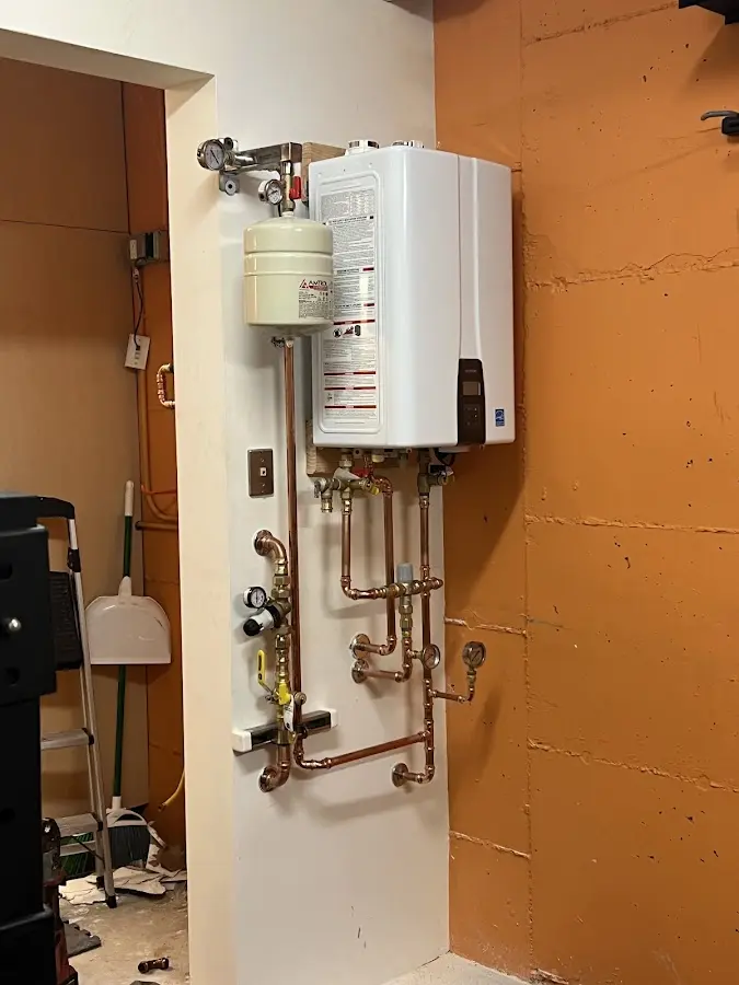 Plumbing technician inspecting water heater connections in Rochester